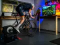 A cyclist trains indoors on a bike trainer, with a screen showing a virtual road. This setup demonstrates how to set up a bike trainer for immersive cycling.