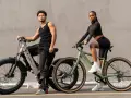 A man and woman pose with their electric hybrid bikes, showcasing a blend of urban style and off-road capability.