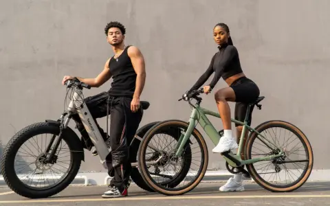 A man and woman pose with their electric bikes. This shows what a hybrid bike is good for: versatile riding on various terrains, blending comfort and performance for urban commutes or light trails.