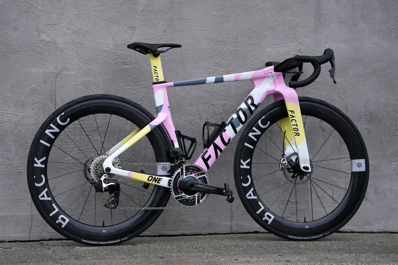 A vibrant pink, yellow, and grey Factor aero bike with black 